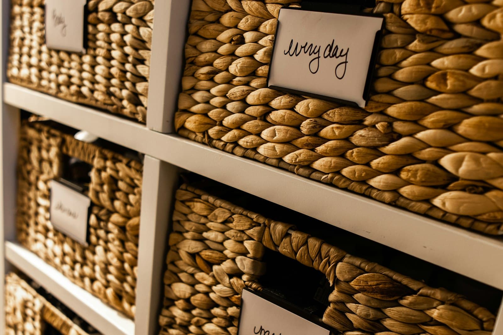 Woven storage baskets on open shelving, one labeled 'everyday,' keeping frequently used kitchen items sorted and within easy reach.