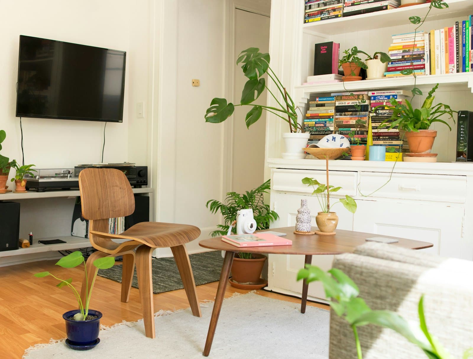 A small, well-arranged living space with a compact wooden chair, round side table and a well-organized bookshelf.