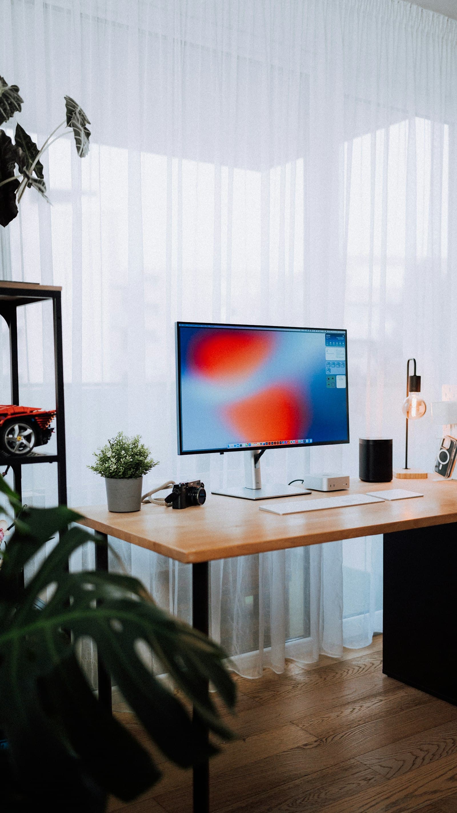 A small, organized home office corner with a desk, task lamp and ergonomic chair.