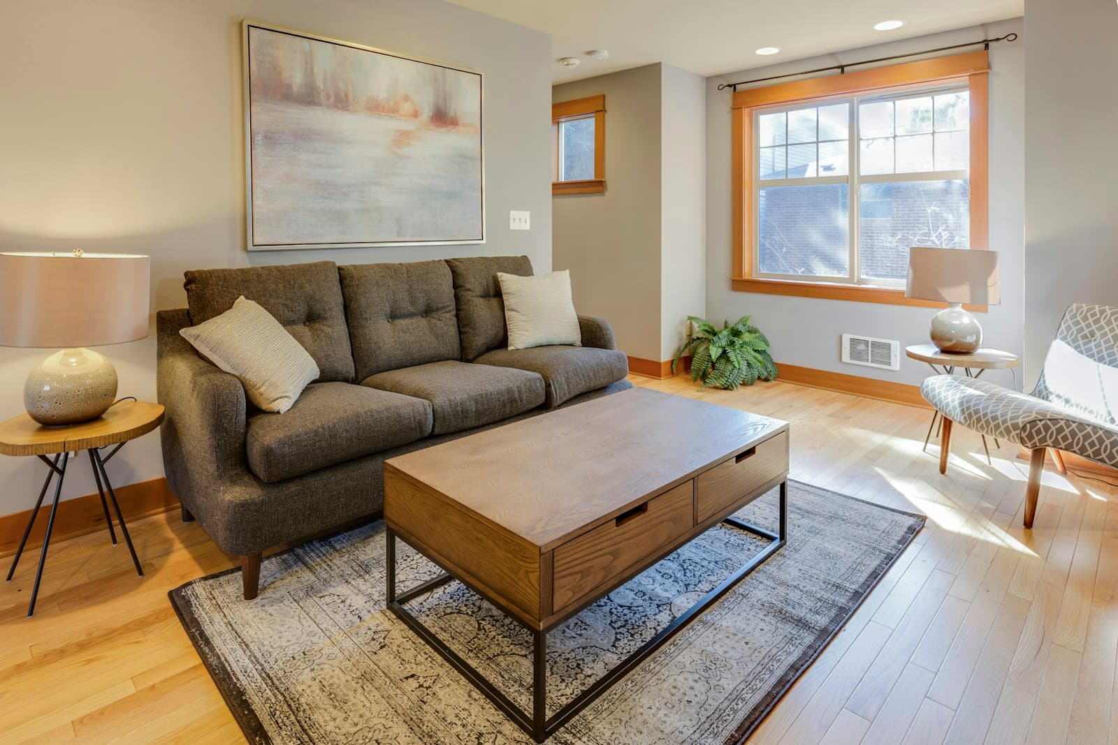 A small, sunlit living room made to feel bigger with a compact sofa, a storage coffee table and an uncluttered layout near the window.
