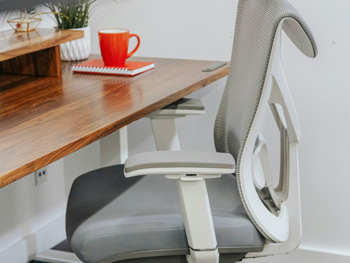 A compact chair pulled up to a warm wooden desk, sized to fit a smaller home office without crowding the room.