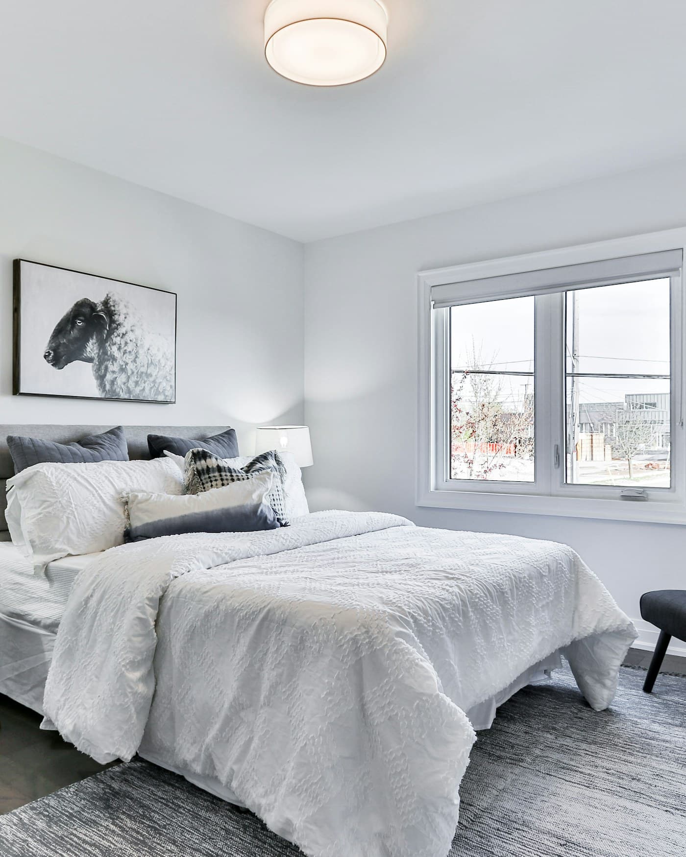 A calm, small bedroom lit by a warm bedside lamp instead of an overhead fixture.