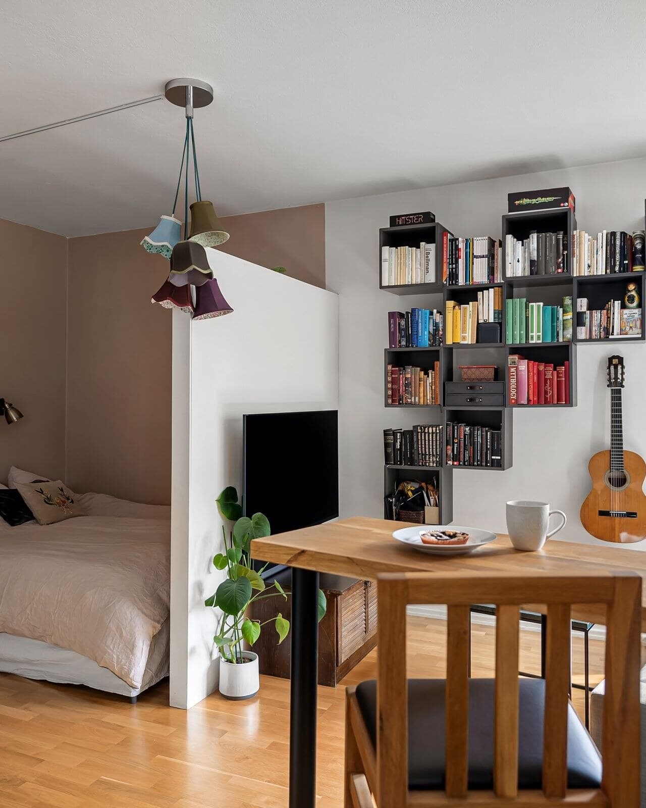 A compact, well-organized studio living area with built-in wall shelving and a cozy reading nook