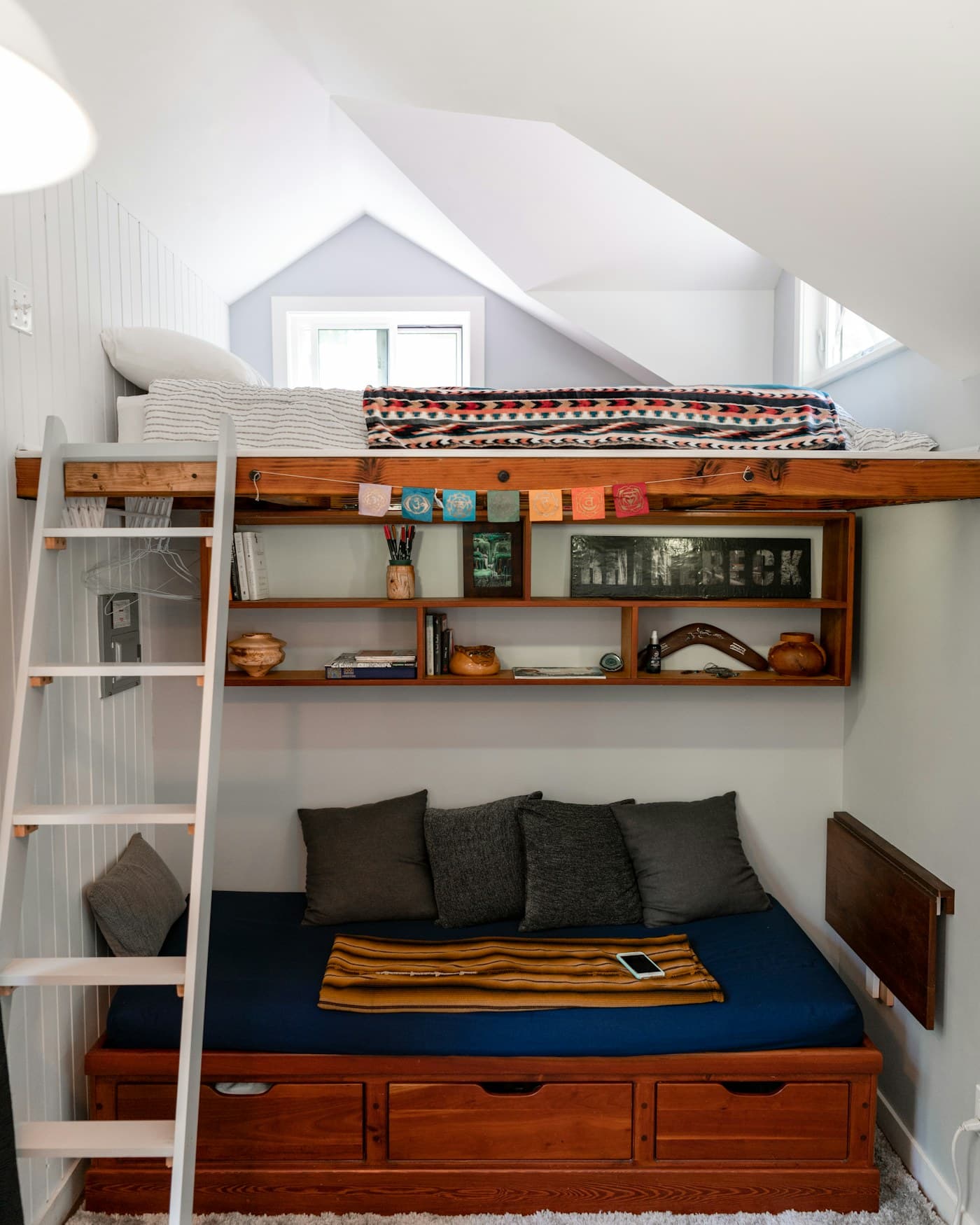 A built-in loft bed with open shelving and under-bed storage drawers in a small bedroom