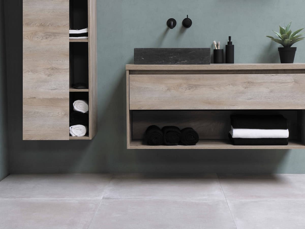 Wood kitchen cabinetry with a closed drawer for utensils and an open shelf holding neatly folded linens, mixing hidden and visible storage within easy reach of the counter.